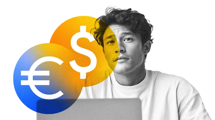 Một người đang học trên máy tính xách tay, bên cạnh các đồng xu euro và đô la